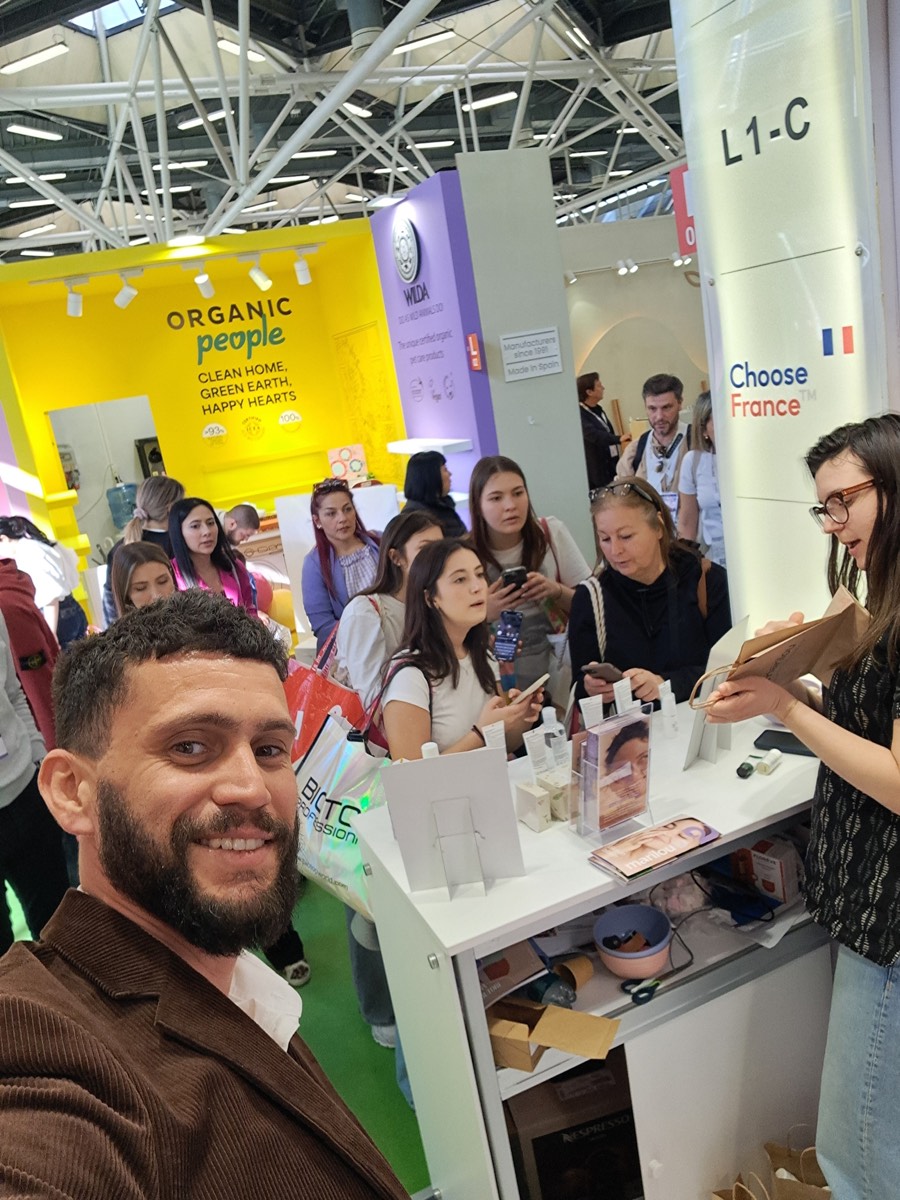 Gabriel Cohen sur le pavillon France d'un salon international de cosmétique, devant le stand bondé d'une marque française qu'il accompagne à l'export