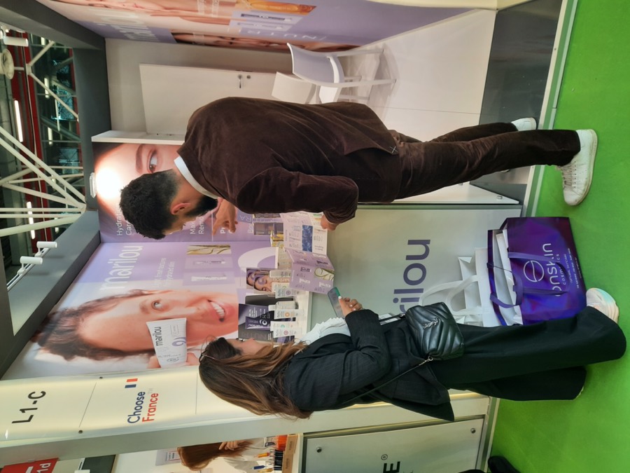 Gabriel Cohen présente une marque cosmétique française à une cliente sur son stand à un salon export international